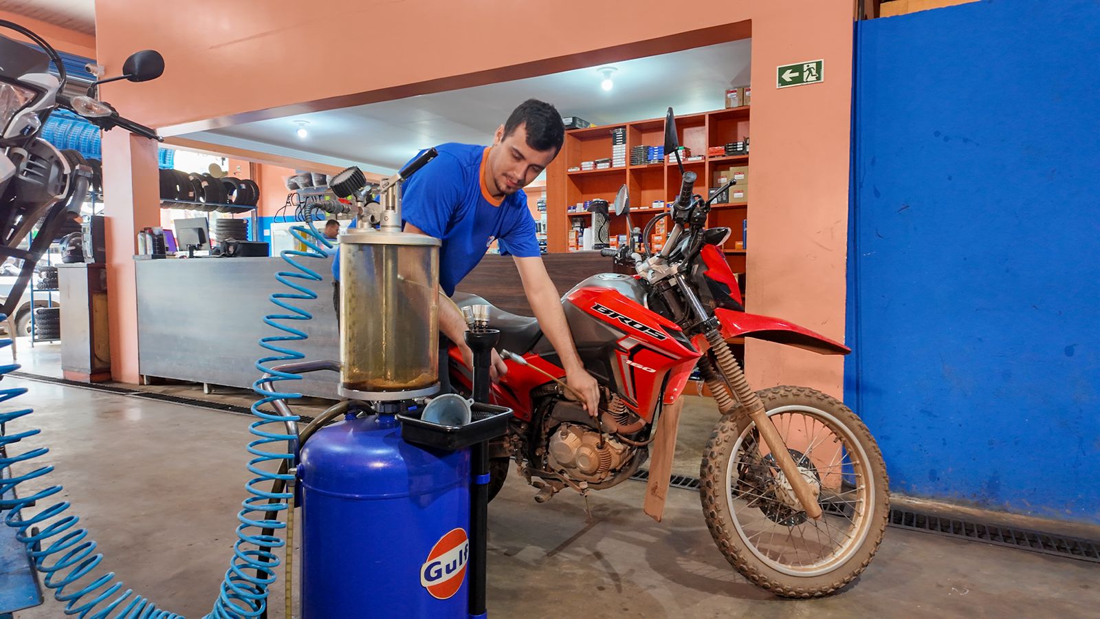 Mecânico da Lider fazendo troca de óleo por sucção em uma Honda Bros dentro da loja